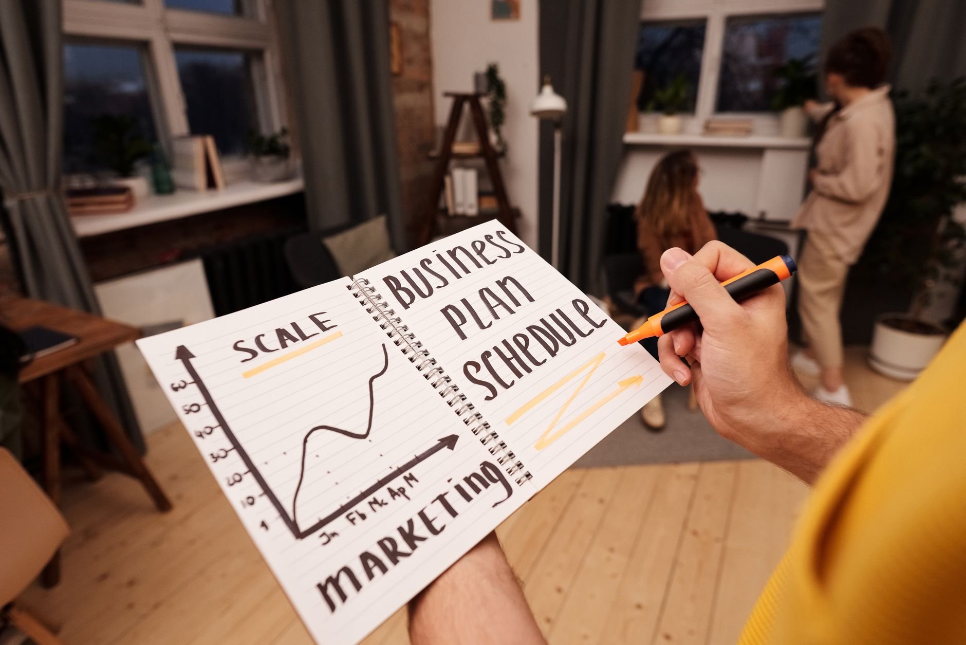Person holding a notebook with planning details and graph for business strategy.